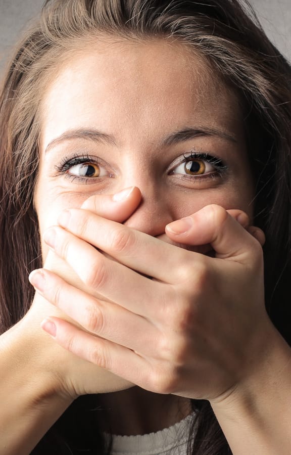 Woman holding both of her hands over her mouth
