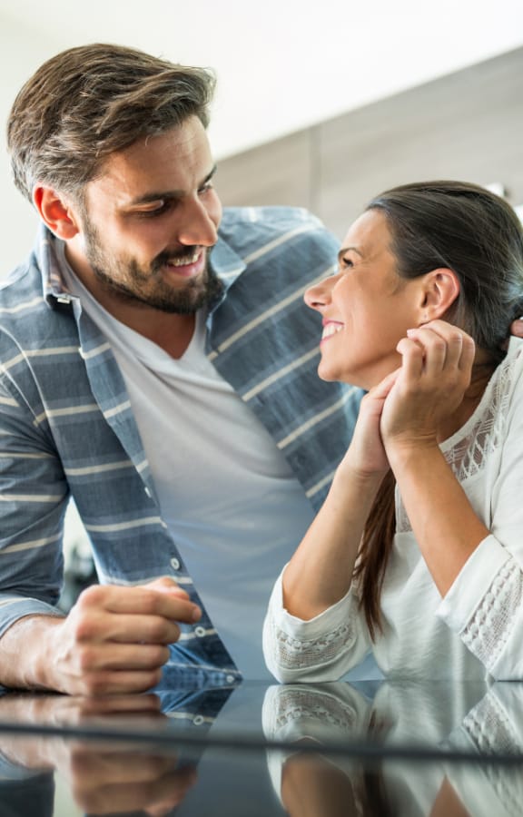 Couple sitting in their kitchen looking at each other and smiling