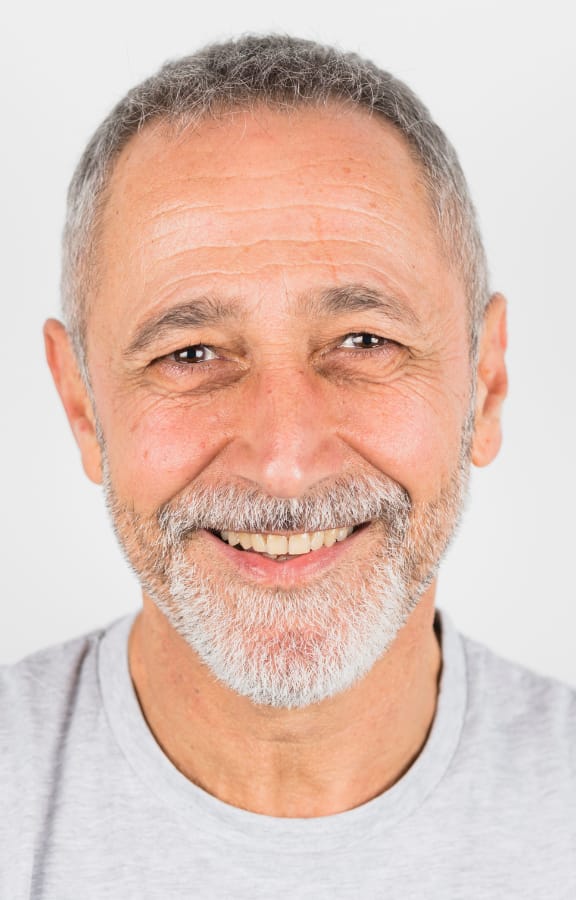 Mature man with beard smiling and showing his upper teeth