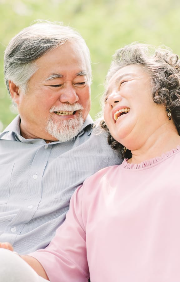 Mature couple sitting on a park bench looking into each others eyes and smiling