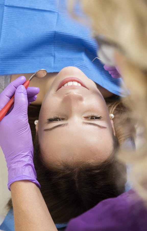 Woman laying back in detal chair getting her teeth checked out