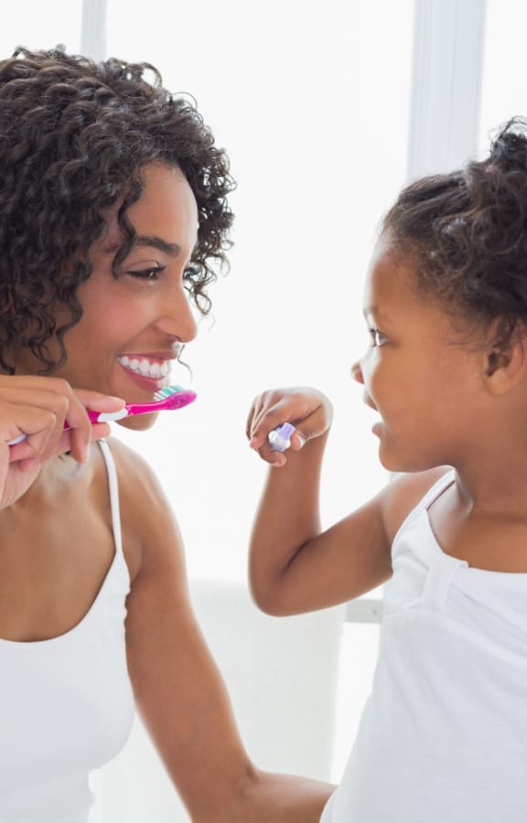 Mother showing her daughter how to brush her teeth