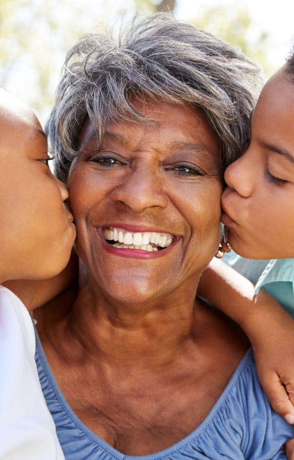 Two grandchildren kissing their grandmother on the cheeks