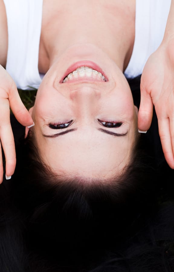 Woman laying on the grass with her hands next to her face