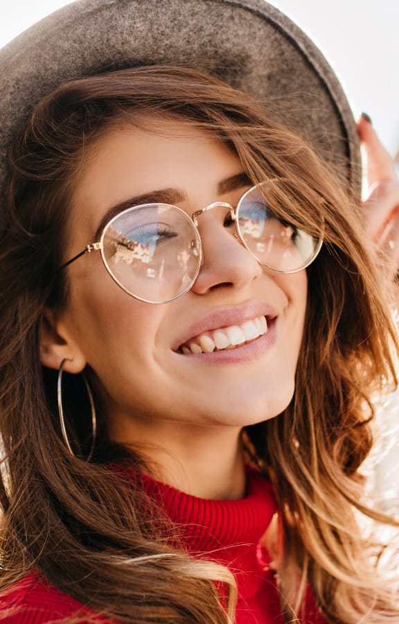 Woman wearing sun glasses and nice hat looking back over her shoulder