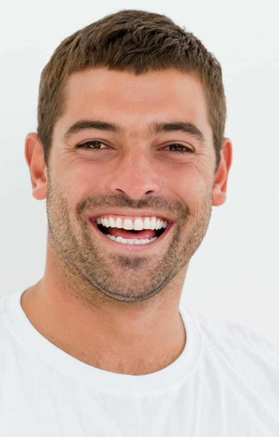 Man smiling in front of white wall